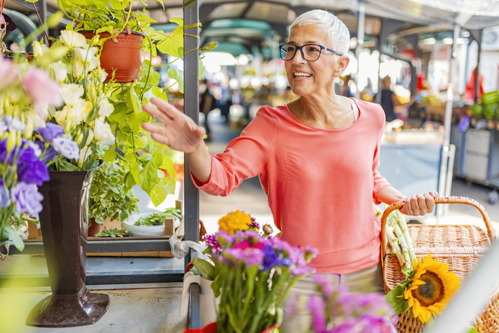 Senior woman smiles and reaches for fresh flowers at a farmers market in Downer's Grove, Illinois