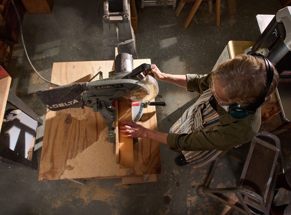 senior uses saw to complete woodworking task inside shop