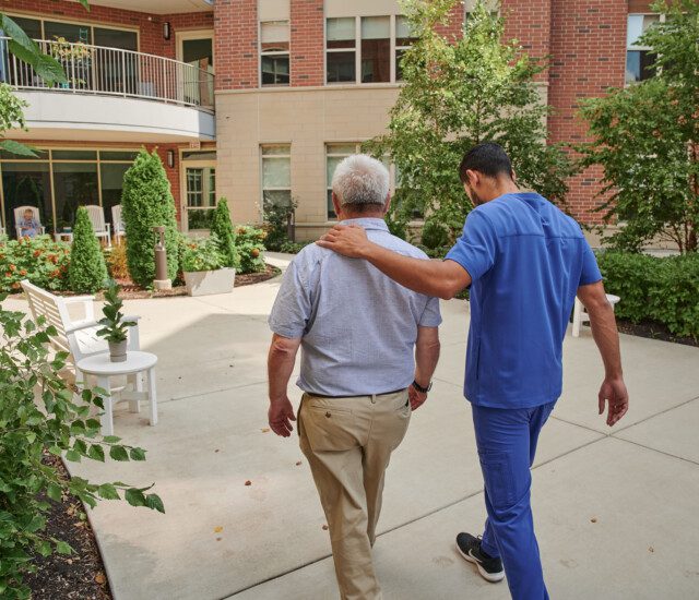 senior man walks and talks with caretake on scenic outdoor path