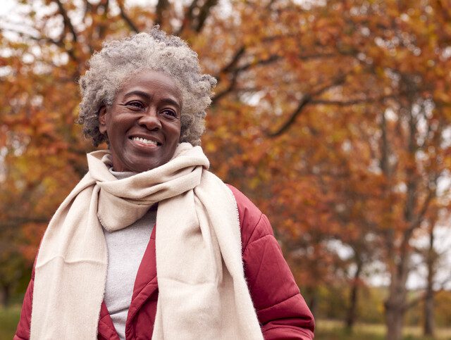 Senior woman out for a walk smiling happily during fall.