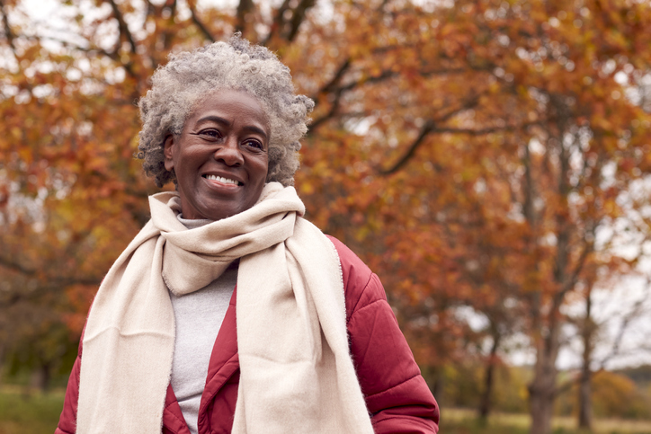 Senior woman out for a walk smiling happily during fall.