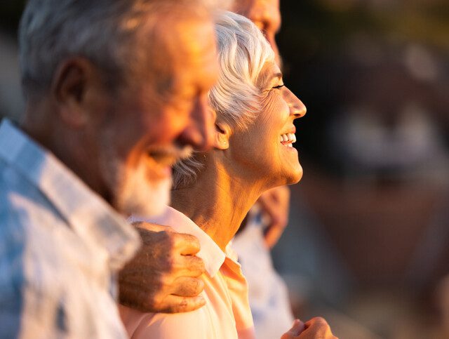 Senior woman smiling happily amongst a group of friends.