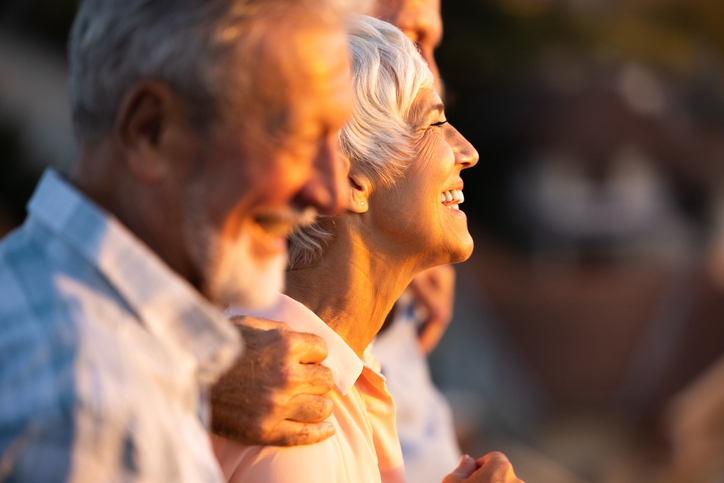 Senior woman smiling happily amongst a group of friends.