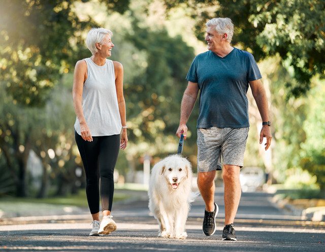 Couple happily strolling with their dog.