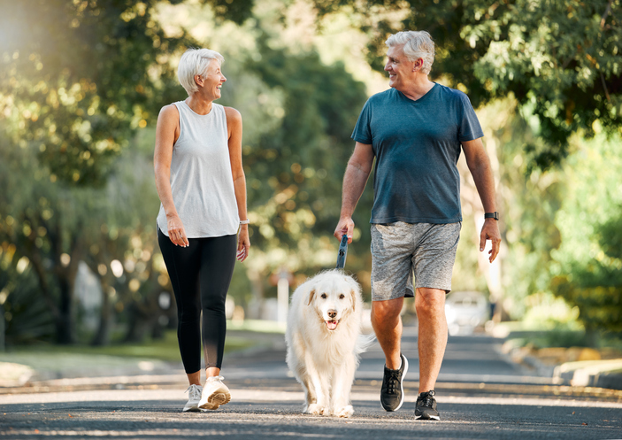 Couple happily strolling with their dog.