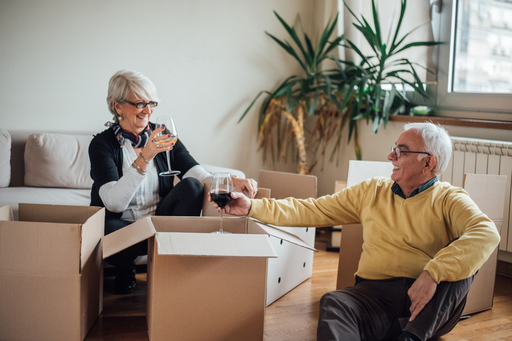 Senior couple clinking wine glasses as they unpack boxes.