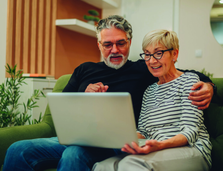 Senior couple using laptop while sitting on a couch at home
